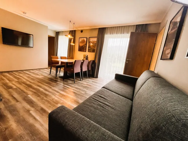 Wohn-/Essbereich mit ausziehbarem Schlafsofa und Zugang zu Balkon