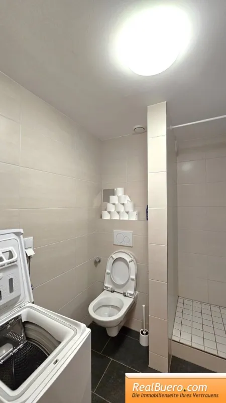Badezimmer mit Dusche, Handwaschbecken, Toilette und Waschmaschinenanschluss