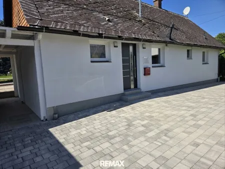 Haus mit gepflastertem Vorhof und Parkmöglichkeiten.
