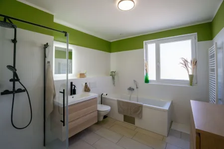 Badezimmer mit Waschtisch, Dusche, Wanne und Sprossenheizkörper
