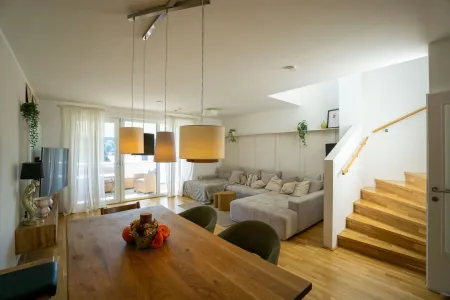Wohnbereich mit Treppe ins Obergeschoß und Ausgang auf den Balkon