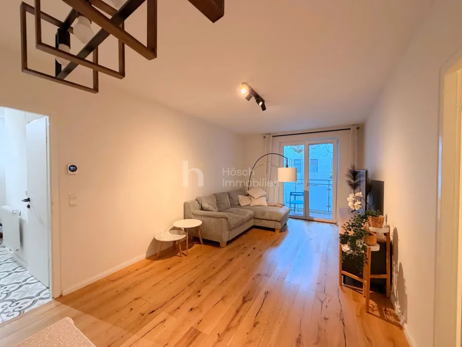 Wohnzimmer mit Sofa und Balkonzugang