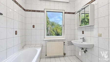 Helles Badezimmer mit Badewanne und Fenster