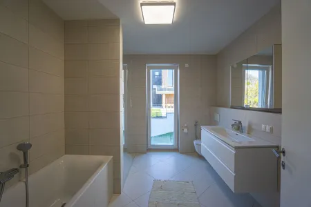 Badezimmer mit Wanne, bodengleicher Dusche, Waschtisch, Spiegelschrank und WC